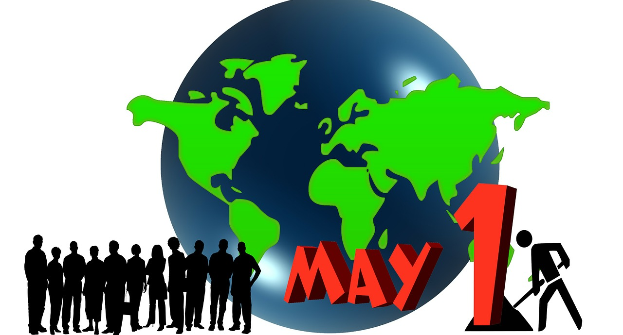 Eine Weltkugel mit grünen Kontinenten, davor Siluetten von Menschen. Daneben der Schriftzug 'May 1'.